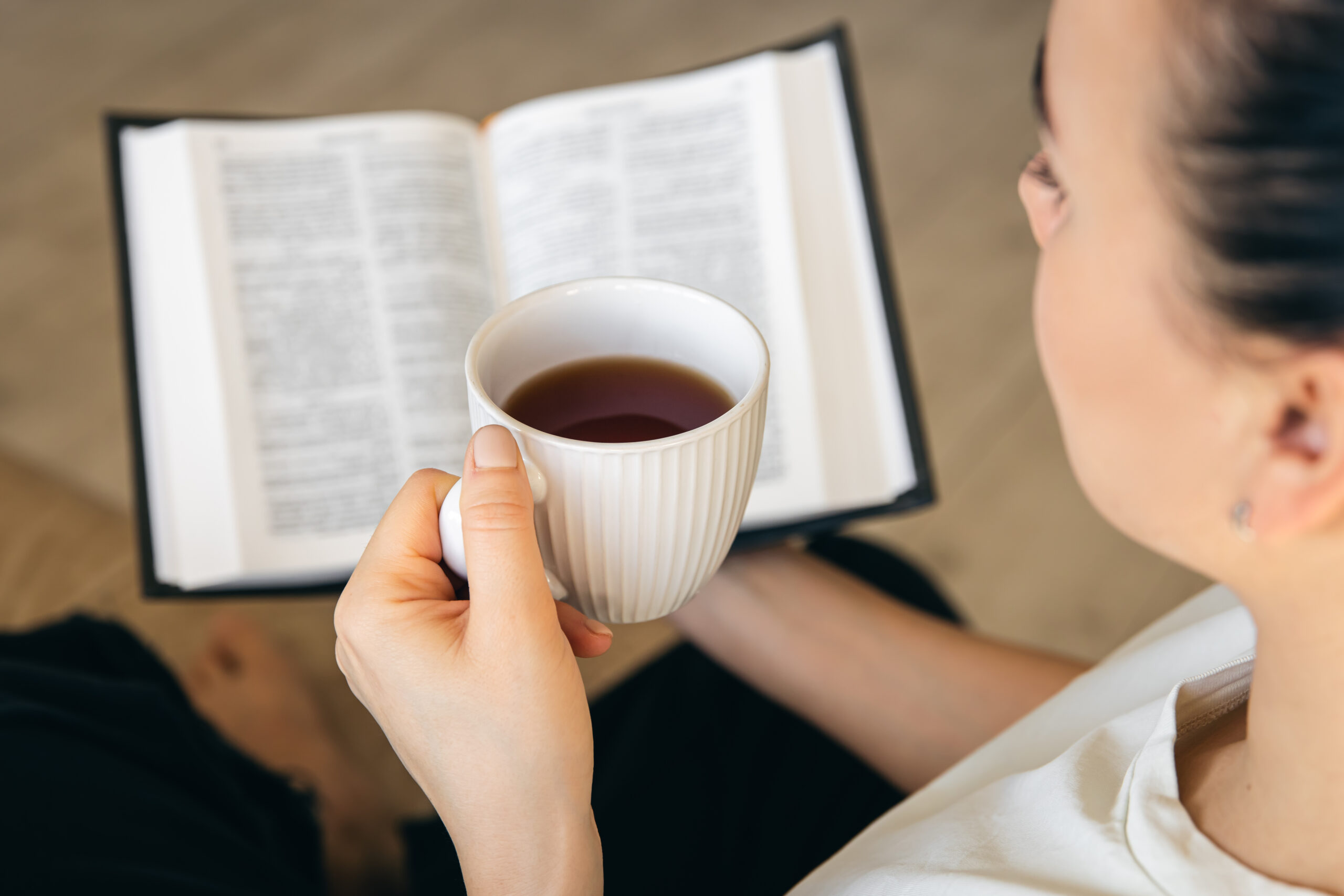 close-up-young-woman-drinking-hot-tea-reading-favorite-paper-book
